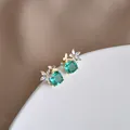 Dettaglio macro di orecchini a farfalla dorati con pietre verdi e fiori di cristallo - Oro (Verde)