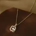 Macro detail of dancing zircon stone within square gold geometric pendant necklace - Gold