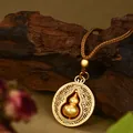 Dettaglio della collana con ciondolo a zucca in oro opaco con cordino intrecciato marrone - Stile Motivo Floreale Traforato Con Piccola Zucca (XL00325)