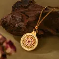 Collana con pendente mandala dorato e pietre rosse su sfondo in legno rustico - Stile Rubino Mandala Stellare Oro (XL00328)