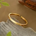 Dettaglio macro del bracciale aperto dorato con texture opaca e incisione in rilievo - Bracciale Rigido Aperto con Caratteri in Rilievo (SZ00219) / Oro