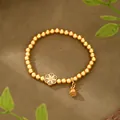 Dettaglio di bracciale in oro opaco con ciondolo a fiore traforato e campanello Fu - Braccialetto con Perline Fiore e Campanello Fu (SL00247) / Oro