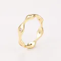 Detailed view of a gold wavy ring with sparkling white cubic zirconia stones - Gold