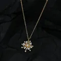 Détail du pendentif flocon doré avec perles et cristaux sur tissu noir plissé - Or