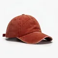 Detail view of washed cotton vintage baseball cap in rust red with curved brim and top eyelets - Blank Style / Orange Red