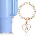 Close-up of golden heart pendant with letter A, O-chain, and lobster clasp on light blue cup - Letter A / White Heart Letter Chain