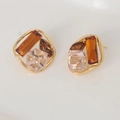 Elegante geometrische gouden oorknopjes met amber en champagne kristallen op witte basis - koffiekleur