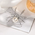 Macro di una spilla a ragno argentata con perla bianca e strass brillanti sulla testa - Ragno d'argento