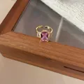 Elegant gold open ring featuring a rectangular pink gemstone and clear side stones - Pink Rectangular Three Stone Open Ring