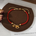 Close-up of red woven bracelet with golden rocking horse pendant and coin charm - Red Gold Patchwork Rocking Horse Coin Style (SL90330)