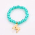 Detail of turquoise seed bead ring featuring a polished gold metal letter M charm - One Size / Letter M Pendant Style (NXR01563)