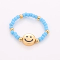Close-up of handmade beaded ring featuring blue beads and a golden smiley face charm - One Size / Sky Blue Gold Smiley Style (NXR01575)