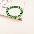 Macro detail of green Evil Eye resin beads with a silver Hamsa Hand charm on a bracelet - Green