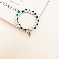Detailed macro shot of white Evil Eye beaded bracelet with silver Hamsa Hand charm - White