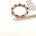 Détails de bracelets extensibles mauvais œil roses et noirs sur un magazine blanc - Rose rouge