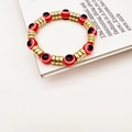 Gros plan détaillé des perles Evil Eye rouges et séparateurs dorés sur le bracelet - Rouge
