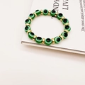 Elastic beaded bracelet with green evil eye charms and gold spacers on white background - Dark Green