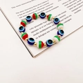 Close-up of Evil Eye Christmas beaded bracelet with Fatima palm and metallic gold spacers - Tri-Color Striped With Double Charms (Style 4)