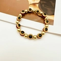 Dettaglio macro del bracciale elastico Evil Eye con perle dorate e ciondoli colorati - Marrone