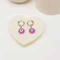 Detailansicht der violetten Evil-Eye-Ohrringe auf einem herzförmigen weißen Steintablett - Lila (Stil 3)