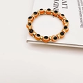 Detailed close-up of orange Evil Eye beaded bracelet with golden metal spacers on a magazine - Orange