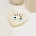 Nahaufnahme von Evil Eye Ohrringen mit silbernen Reifen auf weißem Herz-Display - Blau (Stil 7)