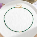 Detail van groene malachiet kralen met gouden spacers en kreeftensluiting op wit bord - Gepolijste groene steen stijl (Type D)