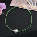 Détail d'un collier de perles vert clair avec perle baroque blanche et fermoir doré - Vert clair