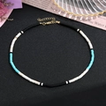 Dettaglio della collana girocollo con pietre colorate e chiusura dorata su sfondo nero - Girocollo Tricolore Blu, Bianco e Nero (Stile L)