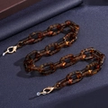 Tortoiseshell acrylic glasses chain with gold lobster clasps on a dark textured background - Tortoiseshell Thick Chain Style