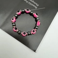 Macro detail of elastic bead bracelet with pink evil eye charms and hematite stones - Pink