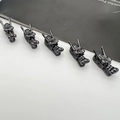 Macro detail of five gun-black alloy dragon head charms for DIY vintage jewelry making - Gunmetal