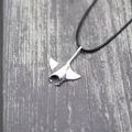 Polished silver manta ray pendant on black woven cord with a purple wood backdrop - Silver