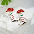 Detail der Weihnachts-Cowboystiefel-Ohrringe mit rotem Hut und Ho Ho Ho-Schriftzug - Cowboystiefel