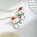 Makroaufnahme von Schneemann-Ohrringen mit roter Weihnachtsmütze und grünem Schal - Schneemann