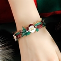 Detailed Christmas charm bracelet featuring Santa Claus and tree charms on model wrist - Bangle