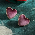 Dettaglio di orecchini a cuore in velluto prugna con montatura dorata e finitura floccata - Stile Floccato Viola
