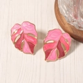 Detailed macro view of enamel Monstera leaf earrings with pink and red color palette - Pink