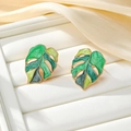 Detailed close-up of monstera leaf earrings with green enamel on a silk tray - Green