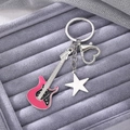 Detailed macro view of Y2K pink guitar keychain with star charm and heart clasp - Pink