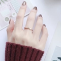 Nahaufnahme eines roségoldenen Titanrings mit drei Diamanten am Finger eines Models - Drei Steine Roségold