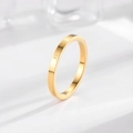 Macro shot of gold Roman numeral engraved stainless steel ring on a white minimalist base - US 4 / Gold