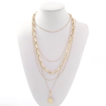 Close-up of layered gold necklaces with sunburst pendant on a white mannequin bust - Five Layer Sunburst Pattern Style (NCN01945) / Gold