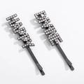 Detail view of two black metal hair clips with rhinestone HAPPY and DRINK letters - Happy Drink Style (NXF00027)
