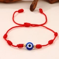 Detail van een rode gevlochten armband met een blauwe boze oog kraal en gouden accenten - Rood Touw Enkel Oog Fijn