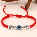 Dettaglio del bracciale intrecciato rosso con ciondoli elefante e perla occhio blu - Corda Rossa Elefante