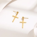 Detailed macro view of gold cross dangle earrings with a polished mirror finish on white surface - Gold