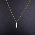 Elegante goldene Titankette mit drei vertikalen weißen Perlen auf grauem Grund - Reis-Süßwasserperlen-Stil (CK1998)