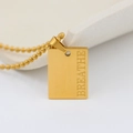 Macro detail of golden rectangular pendant with Breathe engraving and bead chain - BREATHE (New)