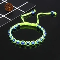 Gedetailleerde macroweergave van fluo-groene gevlochten armband met blauwe boze oog kralen - Fluorescerend Groen (B0038)